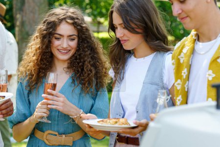 Téléchargez les photos : Les amis et la famille parlent et mangent des spécialités barbecue lors d'une garden party grill d'été. - en image libre de droit