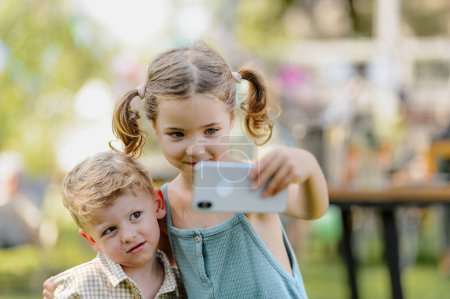 Photo for Cousins taking a selfie at a family garden party. Family reunion at a garden barbecue party. - Royalty Free Image