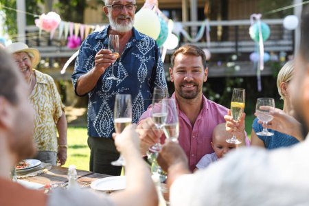Photo for Big family clinking glasses at summer garden party. Celebratory toast at the table. - Royalty Free Image