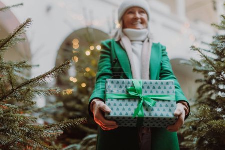 Téléchargez les photos : Femme âgée debout à l'extérieur, tenant beaucoup de cadeaux Chrismtas dans ses mains. Fête du shopping de Noël. - en image libre de droit