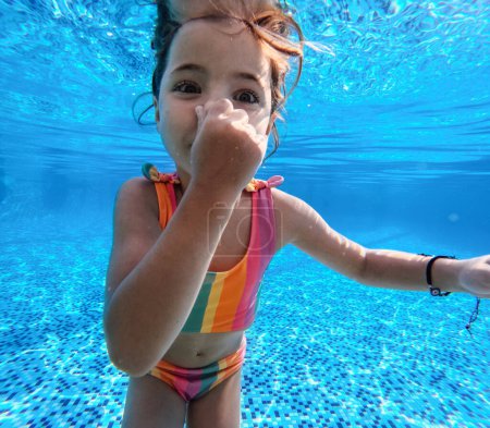Téléchargez les photos : Fille plongée sous l'eau dans la piscine pendant les vacances d'été, jouer dans l'eau. Vacances balnéaires au bord de la mer. Vacances d'hiver ou d'été au bord de la mer. Photographie sous-marine. - en image libre de droit