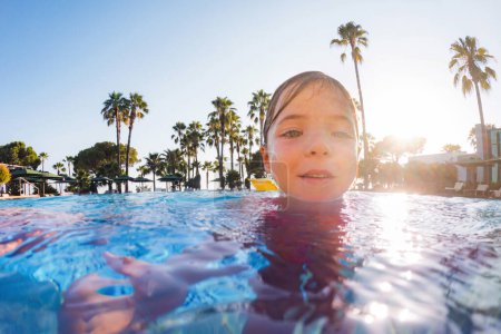 Photo for Little girl learning to swim in the pool during summer vacation. Beach resort vacation by the sea. Winter or summer seaside resort holiday. - Royalty Free Image