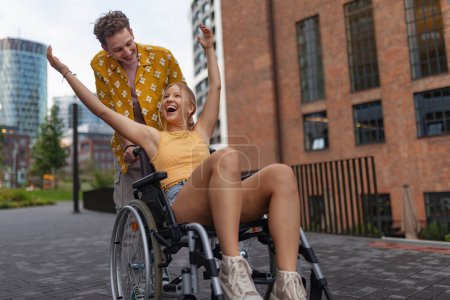 Photo for Beautiful smiling gen Z girl in a wheelchair with her boyfriend. Inclusion, equality, and diversity among Generation Z. - Royalty Free Image