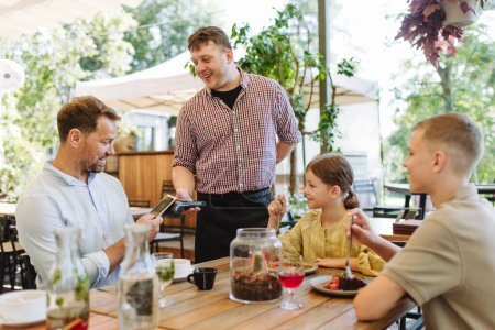 Padre e hijos pidiendo comida a un camarero. Familia monoparental cenando en un restaurante. Concepto del Día de los Padres.