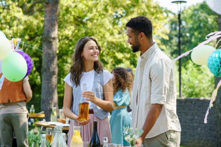 Photo for Friends talking and having fun at a summer grill garden party. Multiracial couple hosting garden party. - Royalty Free Image