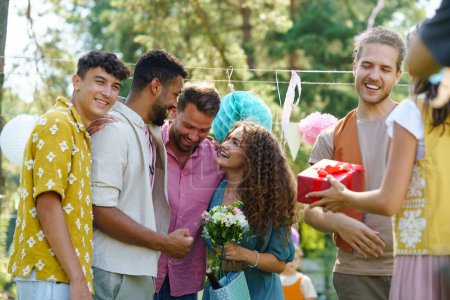 Photo for Garden birthday party with surprise. Friends holding birthday gifts and flowers for birthday girl. Family garden gathering during warm autumn day. - Royalty Free Image
