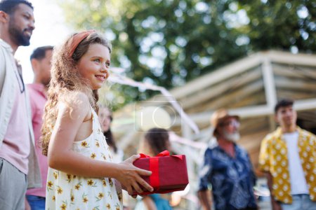 Photo for Garden birthday party with surprise. Portrait of geautiful girl holding birthday gift in hands. Family garden gathering during warm autumn day. - Royalty Free Image
