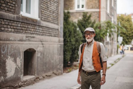 Téléchargez les photos : Portrait d'un bel homme âgé en ville. Homme cool âgé se promenant dans la ville en vêtements à la mode. - en image libre de droit