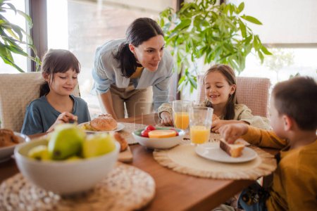 Téléchargez les photos : Mère prépare le petit déjeuner pour les enfants, le matin. Amour maternel et soins pour le ménage et la famille. - en image libre de droit