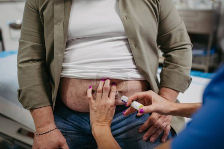 Doctor is injecting insulin into a patients abdomen using insulin pen. Obese, overweight man is at risk of developing type 2 diabetes. Concept of health risks of overwight and obesity.