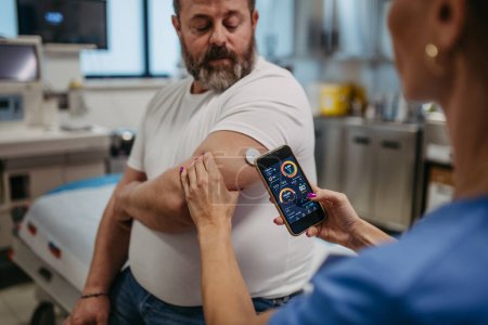 Médecin connectant les patients moniteur de glucose continu avec smartphone, pour vérifier son taux de sucre dans le sang en temps réel. Obèse, l'homme en surpoids est à risque de développer le diabète de type 2. Concept de santé