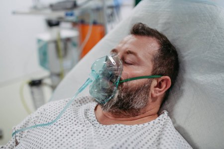 Unconscious patient with oxygen mask on the hospital bed. Man in intensive care unit in hospital.