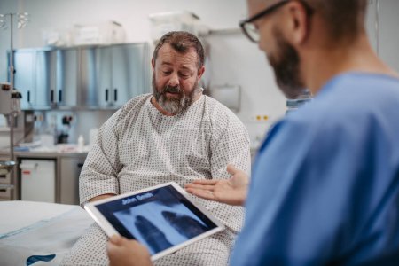 Foto de Médico mostrando un paciente con sobrepeso radiografía de tórax, discutiendo el resultado de la prueba en la sala de emergencias. Enfermedades respiratorias en la salud de hombres de mediana edad. Concepto de riesgos para la salud de sobrepeso y obesidad. - Imagen libre de derechos