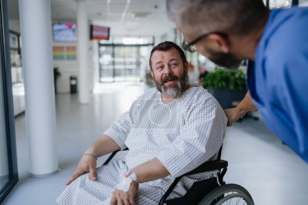 Supportive nurse soothing worried patient in wheelchair. Illnesses and diseases in middle-aged mens health. Compassionate physician talking with stressed patient. Concept of health risks of overwight