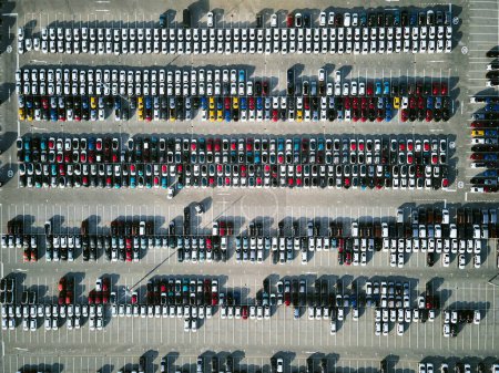 Téléchargez les photos : Vue aérienne d'un parc de stationnement massif dans une usine de fabrication de voitures avec des véhicules nouvellement produits garés en rangées. - en image libre de droit