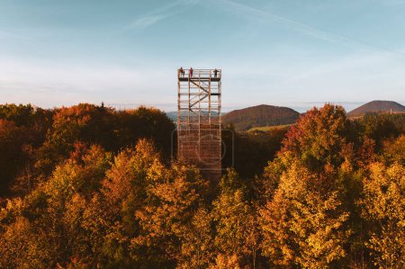 Photo for Aerial view of wooden lookout tower in autumn nature. People stand on the observation tower, enjoying beautiful, serene view of the surrounding landscape. - Royalty Free Image