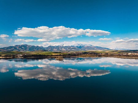 Photo for Aerial view from above the water surface of Liptovska Mara water reservoir on serene nature landscape, High Tatras Mountains in the distance. - Royalty Free Image