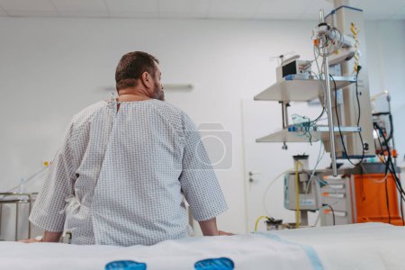 Rear view of overweight patient in hospital gown waiting for the medical examination, test results in hospital, feeling anxious, worried. Patient feeling dizzy, have vertigo and intense pain.