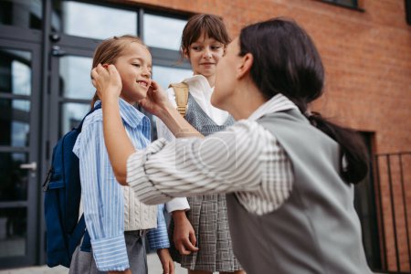 Photo for A hard-working, ambitious mother preparing her daughters for school, saying goodbye to them in front of the school building, and heads to work. Concept of work-life balance for women. - Royalty Free Image