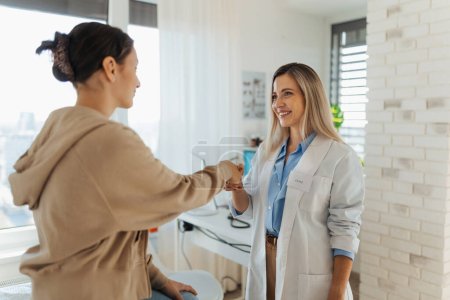 Photo for Teenage patient arriving at appointment with the doctor, shaking hands with female pediatrician, physician. Teen girl have consultation, first visit with gynecologist. Concept of preventive health - Royalty Free Image