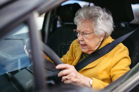 Photo for Focused senior woman driving car alone, holding the steering wheel firmly. Safe driving for elderly adults, older driver safety. - Royalty Free Image