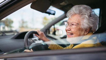 Glückliche Seniorin, die allein Auto fährt und die Autofahrt genießt. Sicheres Fahren für ältere Erwachsene, Sicherheit für ältere Fahrer.