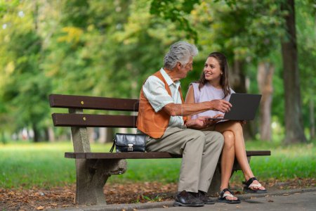 Foto de Cuidador ayudando a un hombre mayor a comprar en línea en una computadora portátil. El riesgo de estafas de compras en línea dirigidas a las personas mayores. - Imagen libre de derechos