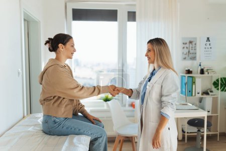 Photo for Teenage patient arriving at appointment with the doctor, shaking hands with female pediatrician, physician. Teen girl have consultation, first visit with gynecologist. Concept of preventive health - Royalty Free Image