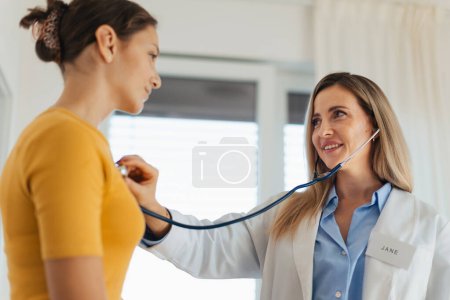 Photo for Doctor listening to girlss breathing, heartbeats using a stethoscope. Teenage girl visiting paediatrician for annual preventive physical examination. Concept of preventive health care for adolescents - Royalty Free Image