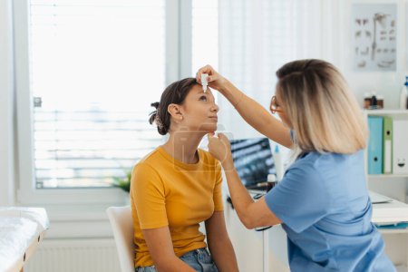 Photo for Pediatrician putting eye drops into girls eyes. Ophthalmologist treating an eye infection, allergy, or inflammation using prescribed eye drops. - Royalty Free Image
