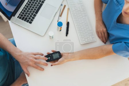 Photo for Diabetologist doctor testing blood sample on glucometer in diabetes clinic. Doctor taking blood sample from boys finger. Paediatric diabetes in teenage boy, young man. - Royalty Free Image