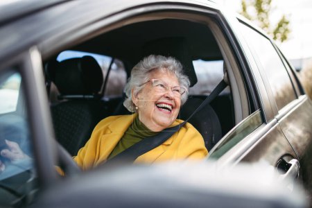 Foto de Feliz mujer mayor conduciendo coche solo, disfrutando del viaje en coche. Conducción segura para adultos mayores, seguridad para conductores mayores. Renovación del permiso de conducción a mayor edad. - Imagen libre de derechos