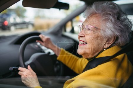 Happy senior woman driving car alone, enjoying the car ride. Safe driving for elderly adults, older driver safety. Driving license renewal at older age.