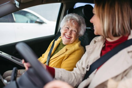 Foto de Nieta conduciendo a su abuela anciana en el coche, llevándola al médico, de compras o al banco. Cuidador de conducir anciana a la iglesia, farmacia. - Imagen libre de derechos
