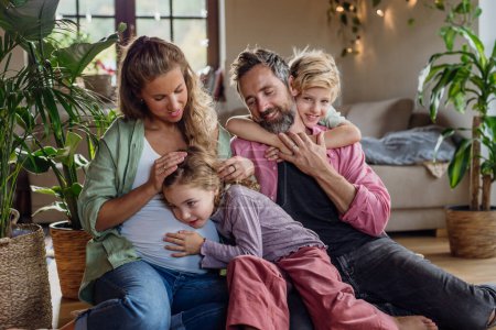 Téléchargez les photos : Portrait de jeune famille à la maison. Mère enceinte avec ses enfants et son mari dans le salon. - en image libre de droit