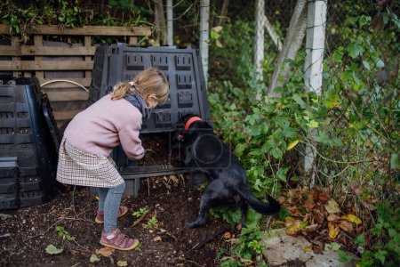 Mädchen entfernen Kompost von einem Komposter im Garten. Konzept der Kompostierung und nachhaltigen ökologischen Gärtnerei.