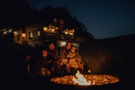 Photo for The family is warming up by an outdoor fire pit, sitting in the evening warmth of the fire, spending quality family time together. - Royalty Free Image