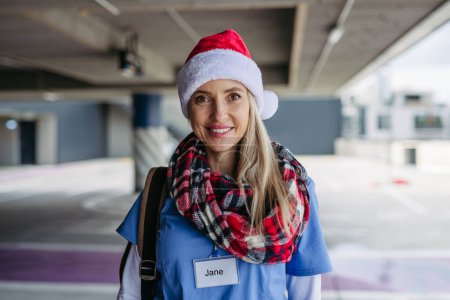 Téléchargez les photos : Portrait de belle infirmière avec chapeau de Noël sur la tête. Travailler à l'hôpital le jour de Noël ou la veille de Noël. Médecin femme travaillant un quart de Noël et ne peut pas être avec sa famille. - en image libre de droit