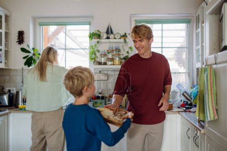 Photo for Young family preparing breakfast together in home kitchen. Healthy breakfast or snack before kindergarden, school and work. - Royalty Free Image