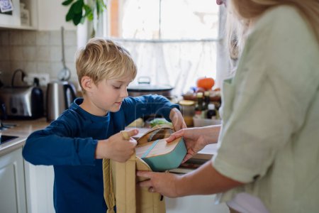 Foto de Mamá está preparando bocadillos para su hijo en la escuela. Poner la lonchera con bocadillos saludables en su bolsa de la escuela para el almuerzo. - Imagen libre de derechos