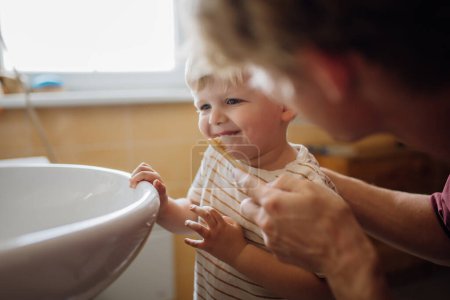 Foto de Padre cepillándose los dientes de los niños pequeños por la mañana. Higiene dental matutina, cuidado de niños pequeños. - Imagen libre de derechos