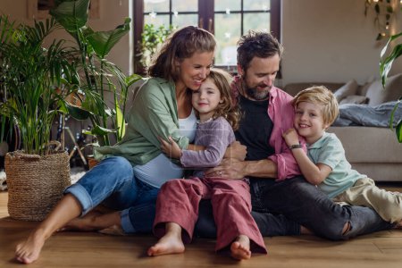 Foto de Retrato de familia joven en casa. Madre embarazada con sus hijos y marido en la sala de estar. - Imagen libre de derechos