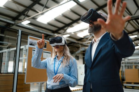 Photo for Engineers talking project using VR, in modern industrial factory. Virtual reality and technology in manufacturing industry, Smart glasses guiding female and male manager through process and planing. - Royalty Free Image