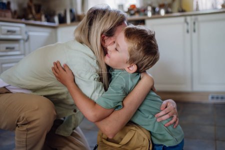 Téléchargez les photos : Mère disant adieu à son fils avant l'école, l'embrassant, l'embrassant dans la cuisine. - en image libre de droit