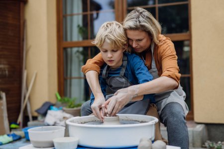 Photo for Mother teaching son how to make pottery on pottery wheel. Child creative activities and art. Boy making pottery, having fun with mom. Happy family moment. - Royalty Free Image
