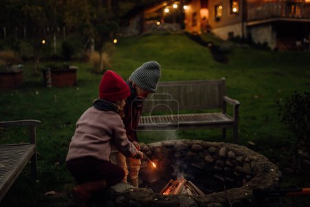 Foto de Familia pasando la noche al aire libre, encendiendo fuego en una fogata. Prents y los niños pasan tiempo familiar de calidad juntos. - Imagen libre de derechos