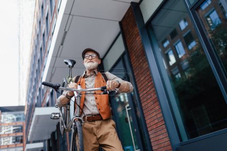 Foto de Un anciano, ciclista que viaja por la ciudad en bicicleta, llevando bicicleta al hombro. Viajeros mayores de la ciudad en bicicleta. - Imagen libre de derechos