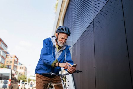 Foto de Un anciano, ciclista que viaja en bicicleta por la ciudad. Viajeros mayores de la ciudad en bicicleta a la tienda de comestibles. - Imagen libre de derechos