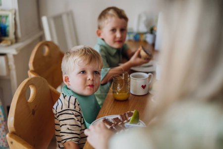 Foto de Familia joven desayunando juntos en la cocina casera. Desayuno o merienda saludable antes del preescolar, la escuela y el trabajo. - Imagen libre de derechos
