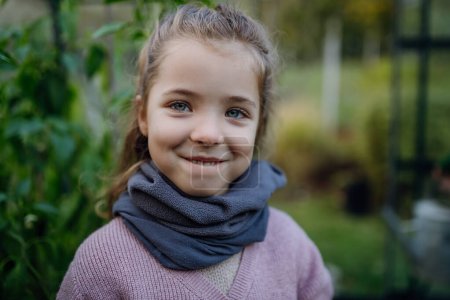 Téléchargez les photos : Portrait de petite fille prenant soin de plantes dans le jardin, pendant les premiers jours du printemps, derniers jours d'automne. Concept de conservation de l'eau dans le jardin et le jardinage familial. - en image libre de droit